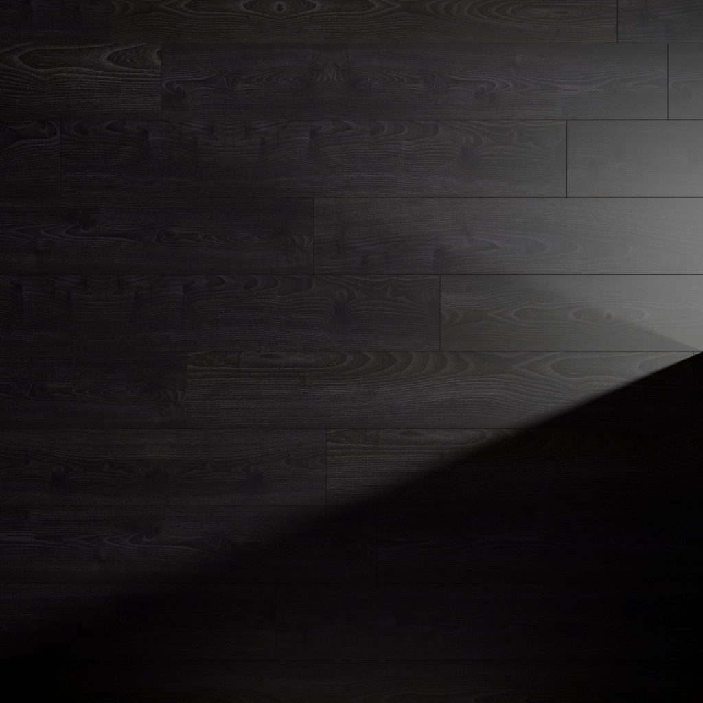 A Beaumont Oak floor with visible grain patterns is partially illuminated by a diagonal beam of light, creating a striking contrast between the lit and shadowed areas.