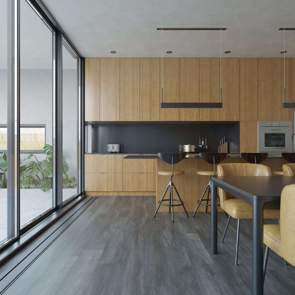 The Cormorant* kitchen features wood cabinets, black countertops, and a matching dining area. Floor-to-ceiling windows provide natural light. Bar stools line the island, with views of potted plants outside.