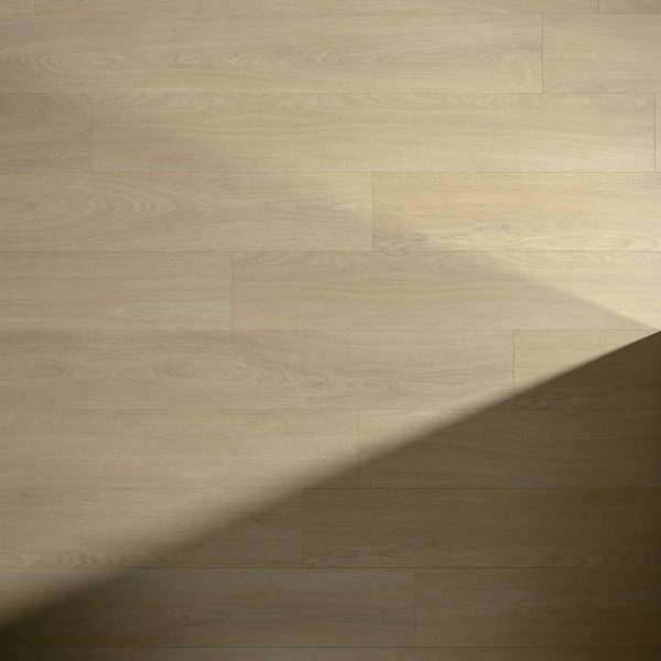 Wheatley* light wooden floor planks arranged in a staggered pattern, with a diagonal shadow cast across the lower right corner of the image.