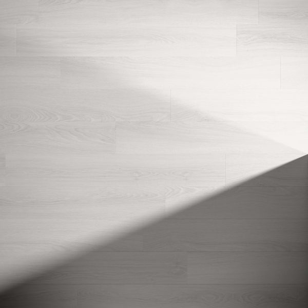 Newborough features a light gray wooden floor with visible grain, highlighted by a diagonal shadow for striking contrast. The minimalistic scene remains uncluttered, emphasizing the floor's elegant appearance.
