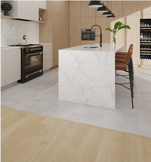 Modern kitchen with light wood cabinets, a marble island with a sink, tall brown bar stools, black pendant lights, and built-in appliances. There’s a plant on the island and a wine fridge on the right.