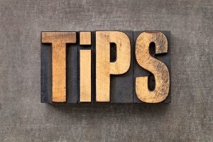 Wooden block letters spelling “TIPS” in a bold, uppercase font are arranged on the right floor of a textured gray surface.